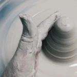 Close up of hands shaping wet clay on a spinning pottery wheel