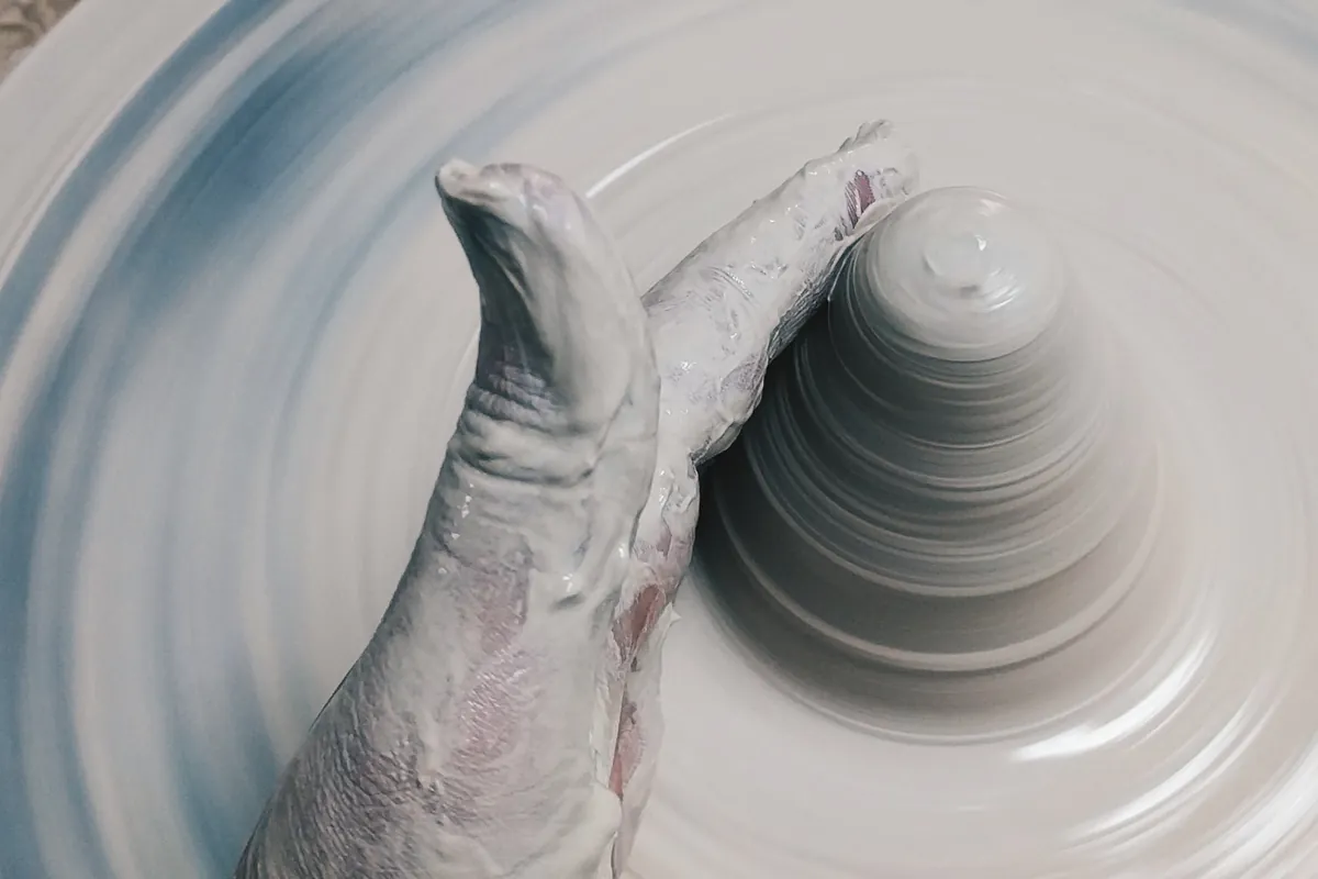 Close up of hands shaping wet clay on a spinning pottery wheel