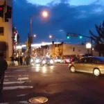 Jersey City street corner at dusk with pedestrians and car lights