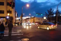 Jersey City street corner at dusk with pedestrians and car lights