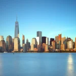 Lower Manhattan skyline glowing at golden hour across the water from Liberty State Park